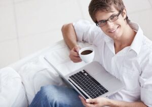 Junger Mann mit Kaffee und Laptop