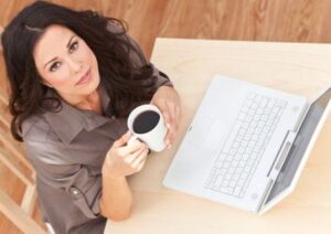 Junge Frau mit Kaffee und Laptop